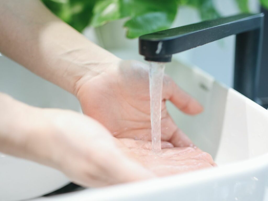 A perosn washing hands under a black tap