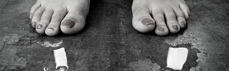 A pair of feet standing slighly apart with a little pool of water around