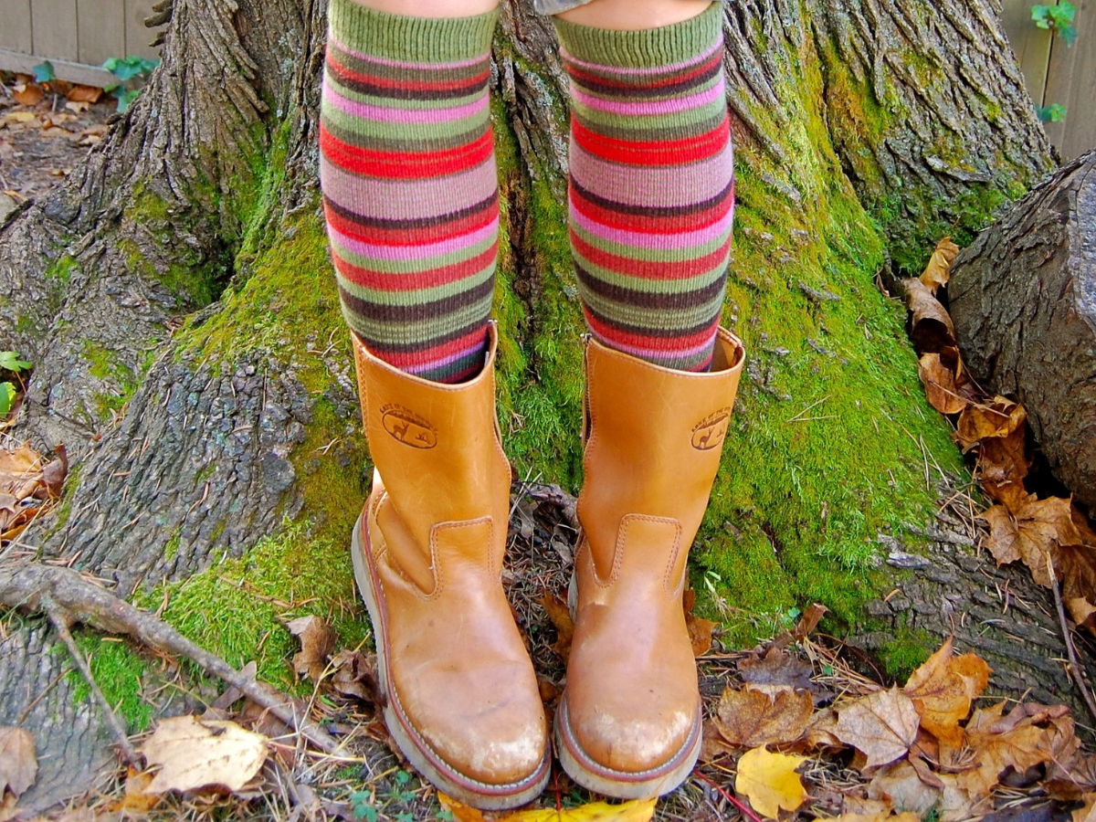 A pair pf legs wearing multi colored socks in wellies